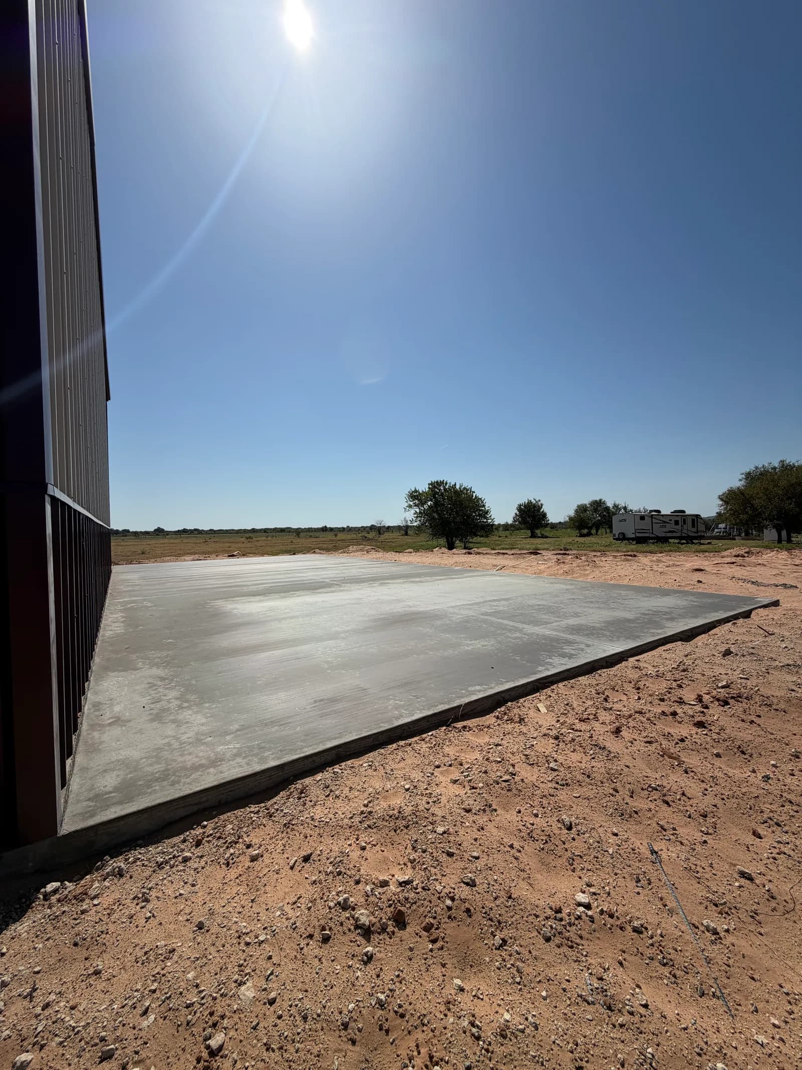 Vernon 24' x 52' RV Cover Foundation — freshly finished slab beside the metal building in Vernon, TX