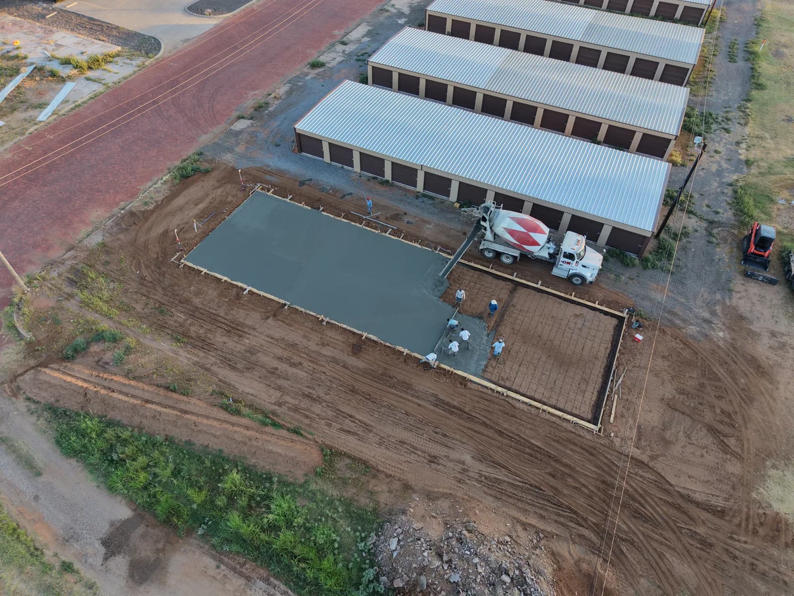 Childress 30' x 100' Storage Building Foundation — aerial view of the slab pour beside existing units in Childress, TX
