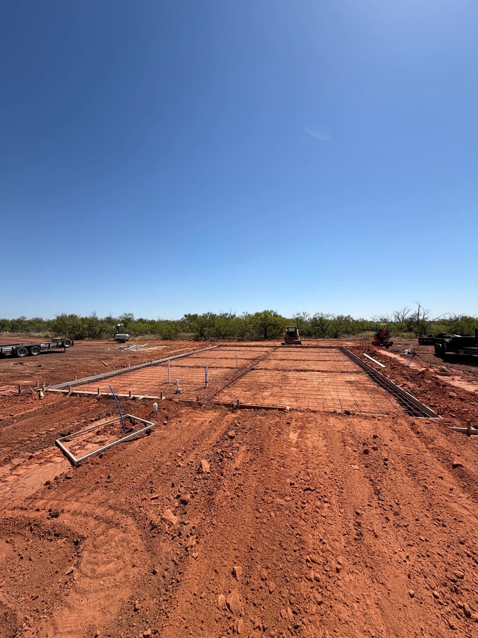 Kirkland 40' x 60' Metal Building Foundation — rebar grid and plumbing rough-in across the pad in Kirkland, TX